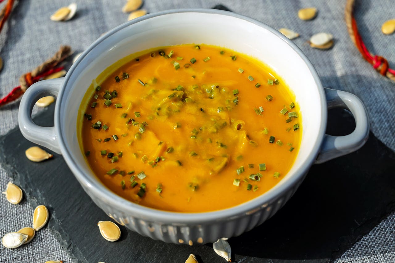 Warm and creamy pumpkin soup garnished with fresh herbs, perfect for a cozy meal.